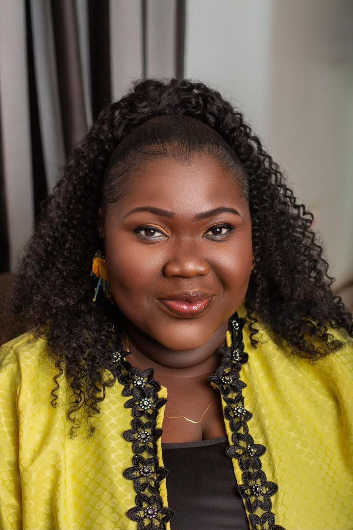 Close portrait of Mercy Sinclear smiling in a yellow jacket with black floral trim